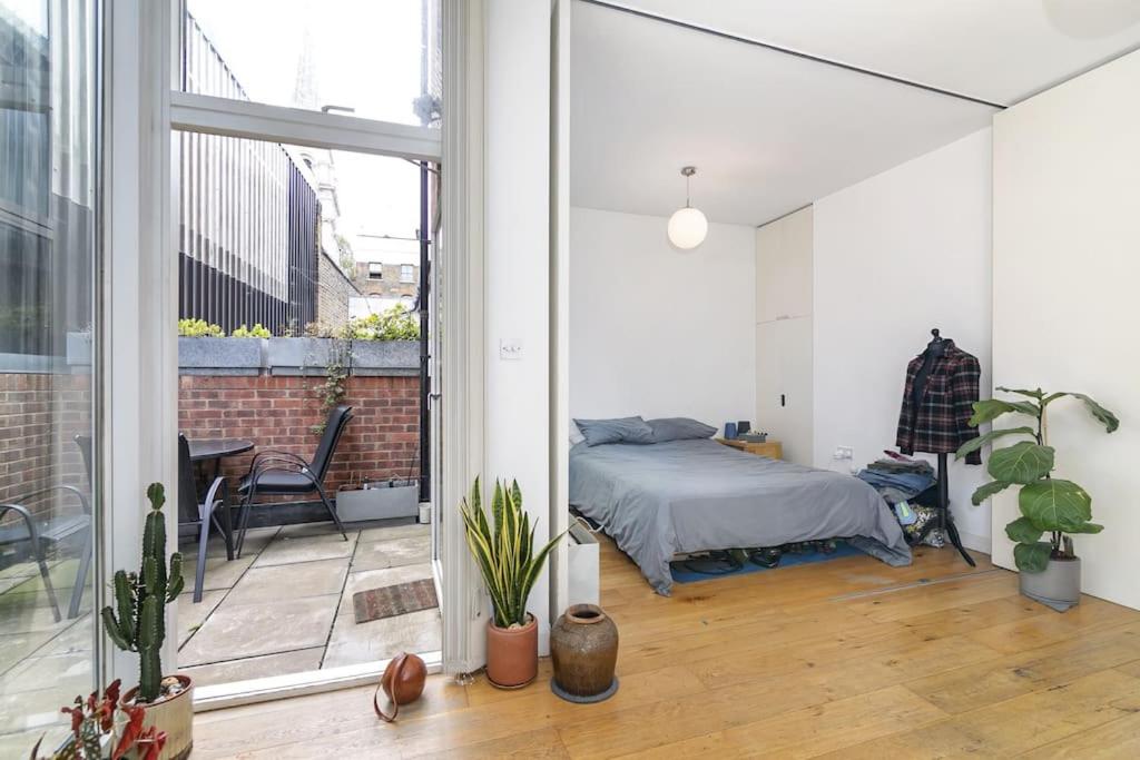 a bedroom with a bed and a balcony at Spitalfields Market Garden Flat in London
