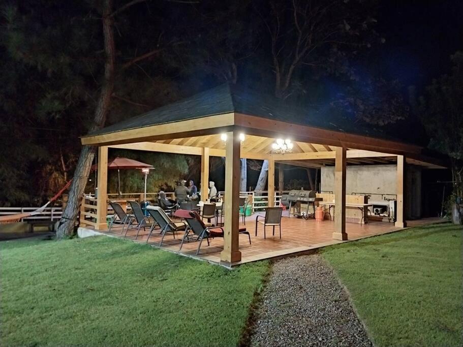 a pavilion with a table and chairs in a yard at Rancho Ecoturistico Grevillea 