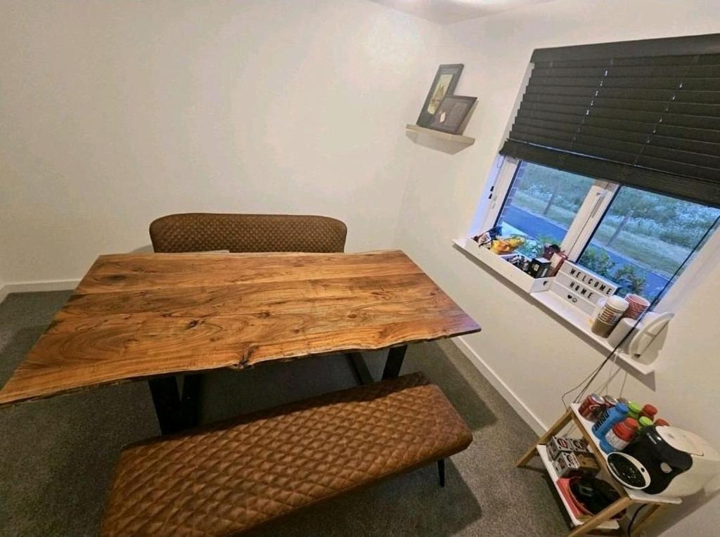 einen Holztisch und zwei Stühle in einem Zimmer mit Fenster in der Unterkunft Darnley southside room in a private home 61 Leggastston Road in Pollokshaws