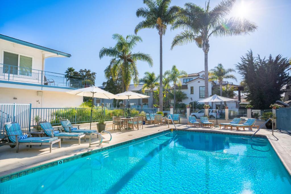 a swimming pool with chairs and tables and palm trees at Pacific Crest Hotel Santa Barbara in Santa Barbara