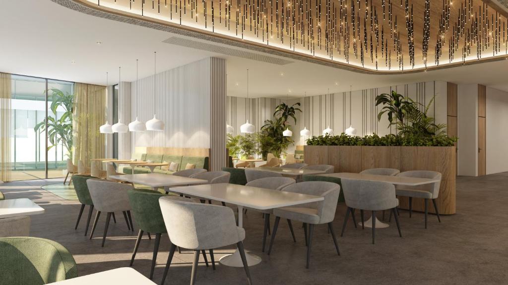 Staybridge Suites Dubai Business Bay, an IHG Hotel في دبي: مطعم بالطاولات والكراسي والنباتات