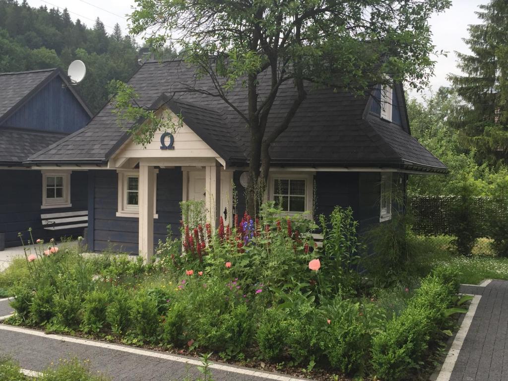 una casa negra con un jardín de flores delante de ella en Chatki Zielarki en Wisła