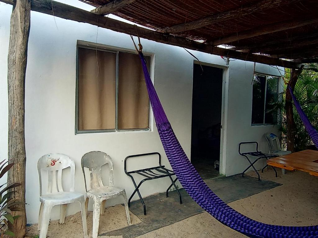 uma casa com duas cadeiras e uma rede no exterior em Casa Adelita em Barra de la Cruz