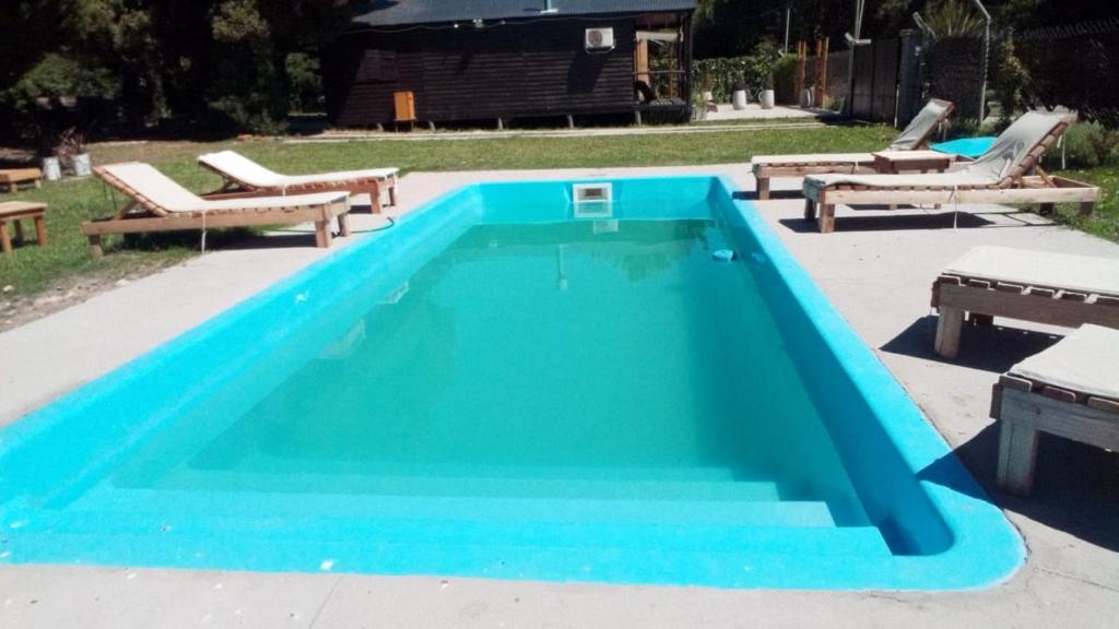 a blue swimming pool with benches around it at Cabaña Los acantilados in Mar del Plata