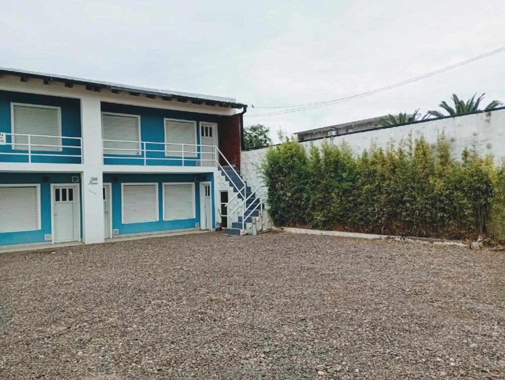 ein Haus mit blauen Türen und einer Kieseinfahrt in der Unterkunft Punta Ninfas 1 in Las Grutas