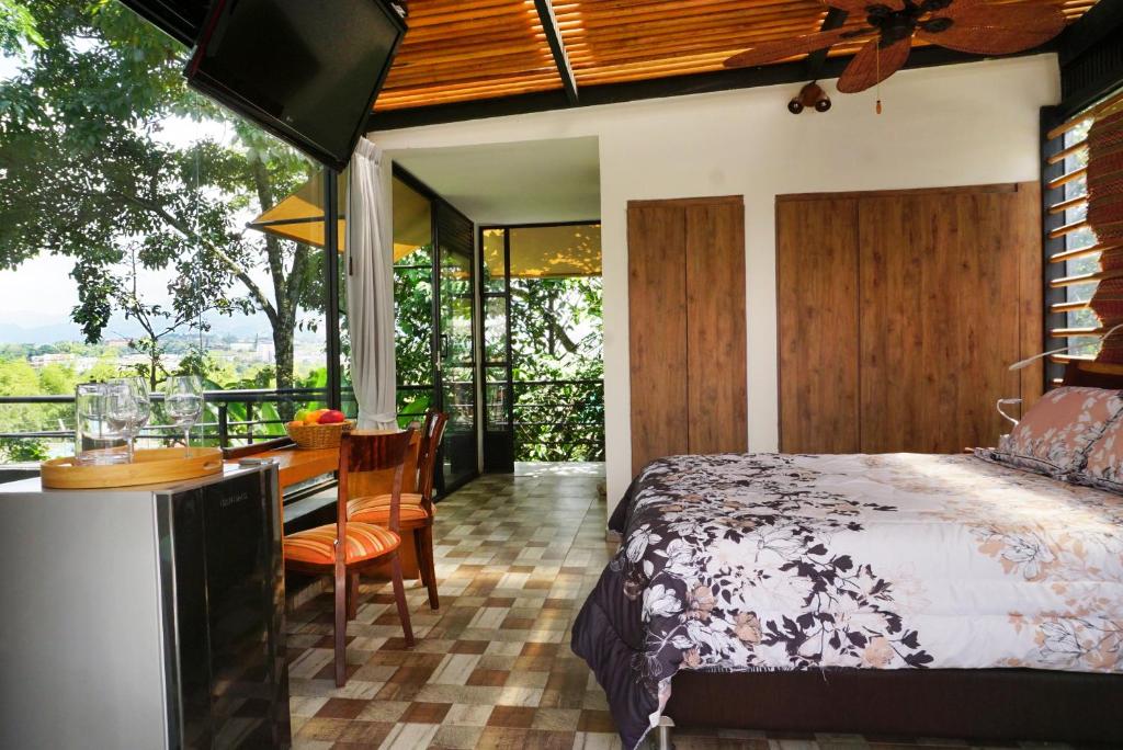 Schlafzimmer mit einem Bett, einem Schreibtisch und einem Tisch in der Unterkunft LALDEA Nirvana Eco Villa in Cerritos in Pereira
