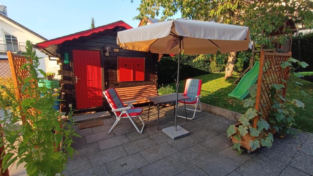 a table with an umbrella and chairs in front of a shed at Kleine Blockhütte im Garten 