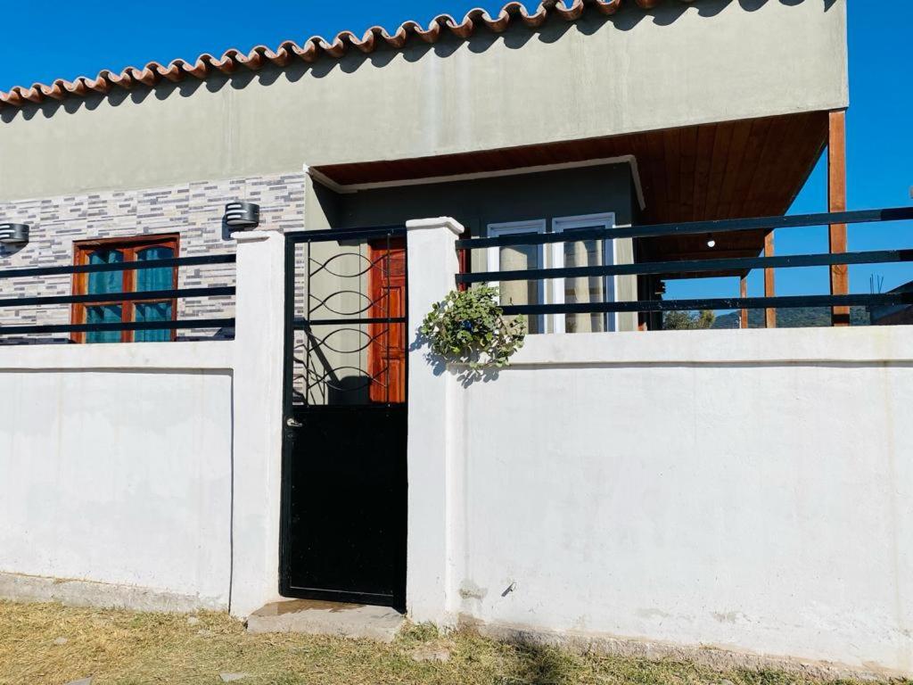 een wit huis met een zwarte deur en een hek bij Sueño de Chicoana in Chicoana