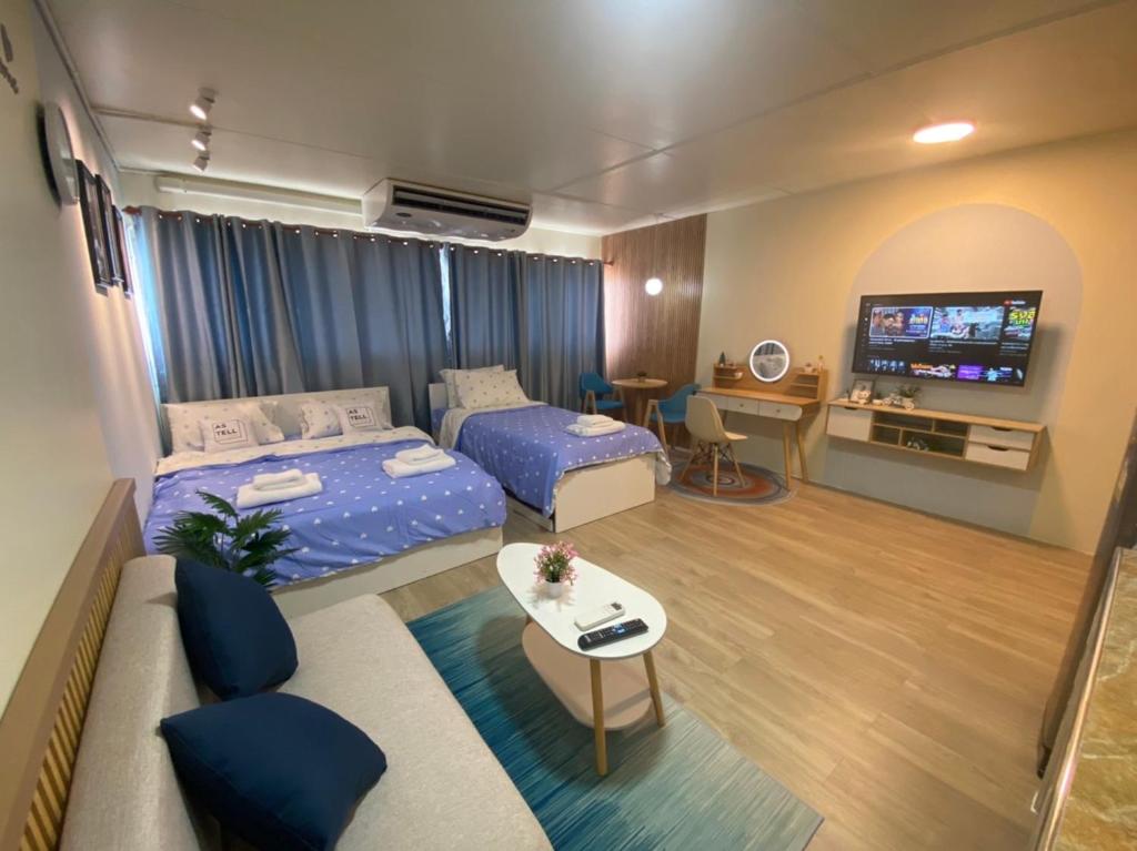 ein Wohnzimmer mit 2 Betten und einem TV in der Unterkunft PTJ Style Condotel คอนโดเมืองทอง P1 in Ban Song Hong