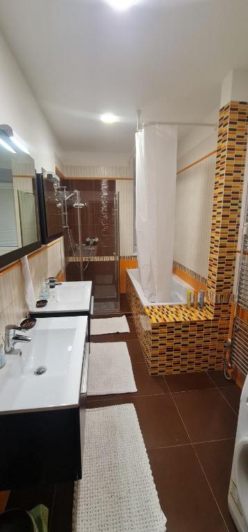 uma casa de banho com 2 lavatórios, um chuveiro e uma banheira. em Luxury 2bed flat with free parking em Bratislava