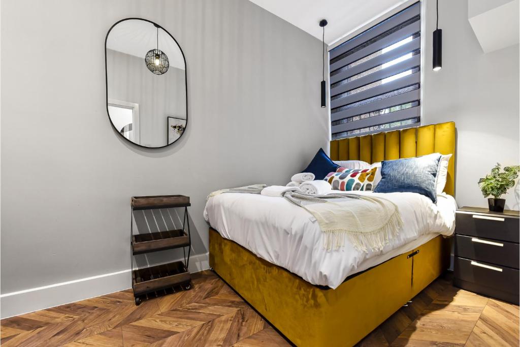 a bedroom with a yellow bed and a mirror at Lovely 2 BR with Grill in London