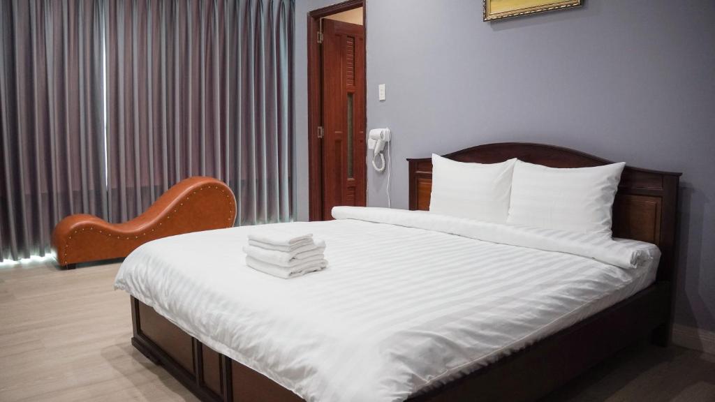 a bedroom with a bed with white sheets and a chair at Bình Minh Hotel in Ho Chi Minh City
