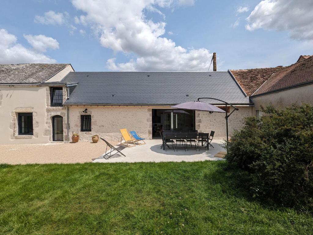 una casa con patio con due sedie e ombrellone di Gîte spacieux et rénové avec jardin, proche châteaux de la Loire, pour 10 pers. - FR-1-590-361 a Huisseau-sur-Mauves