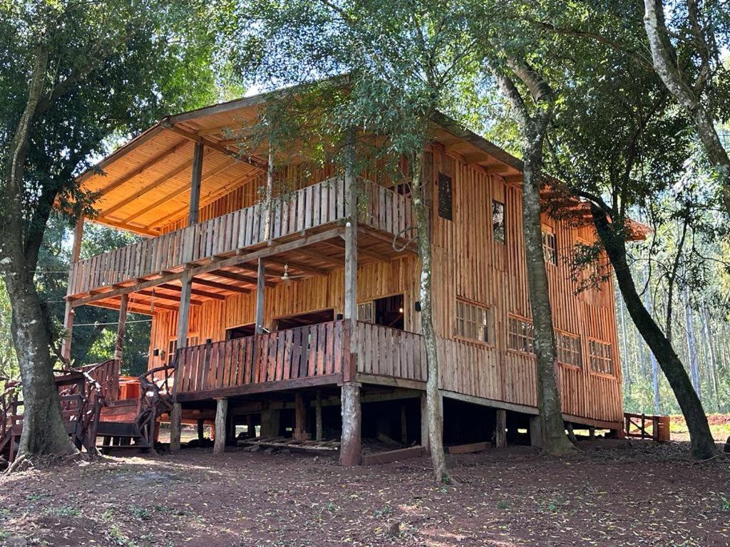 a large wooden house in the middle of trees at La Virginia Rancho Tabay in Jardín América