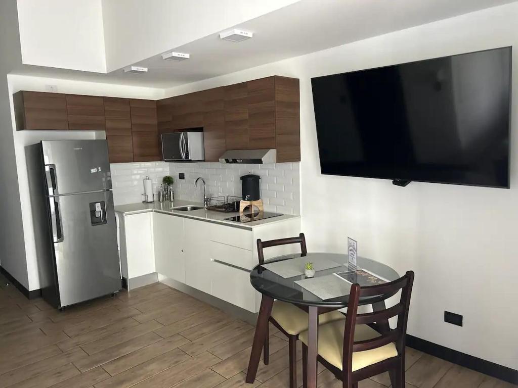 a kitchen with a table and a television on the wall at EÓN 11 - Moderno, vista volcán, aire acondicionado in Guatemala