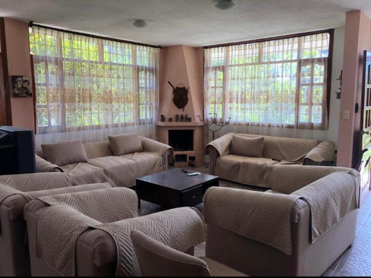 sala de estar con sofás, mesa y ventanas en Tumbaco Ritz, en Quito