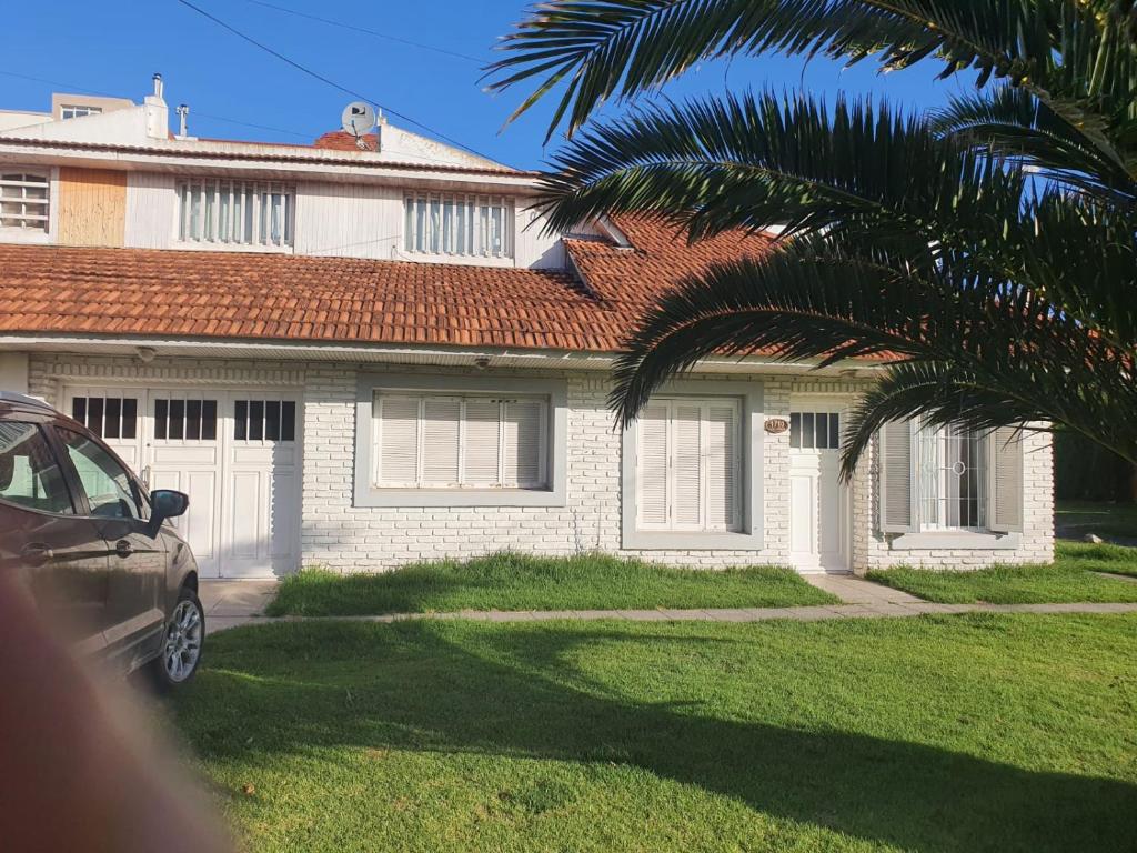 a house with a palm tree in front of it at Casa a 100 metros del mar, garaje doble in Mar del Plata