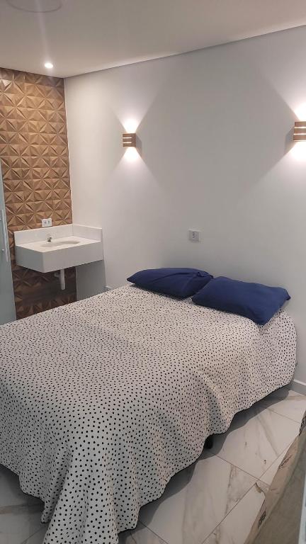 a bedroom with a bed with blue pillows and a sink at Studio 01 in Bertioga