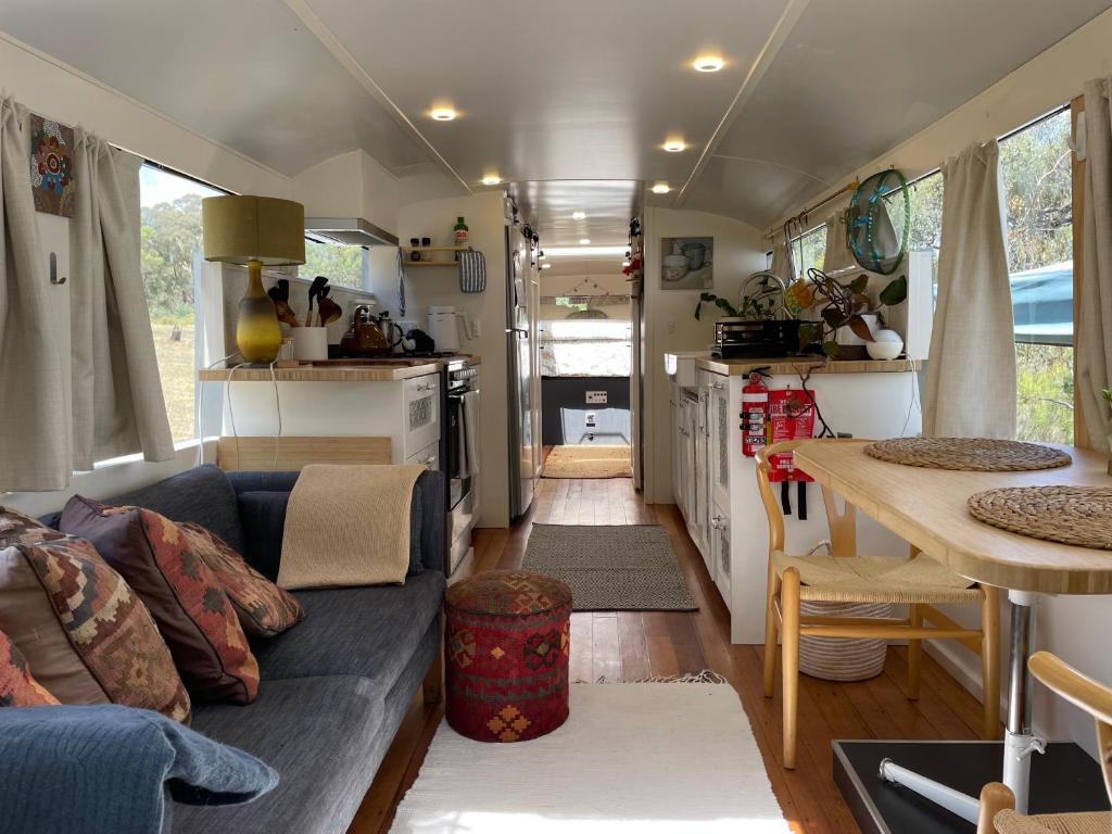 a living room with a blue couch and a kitchen at BUS - Tiny home - 1980s classic with off grid elegance in Faraday