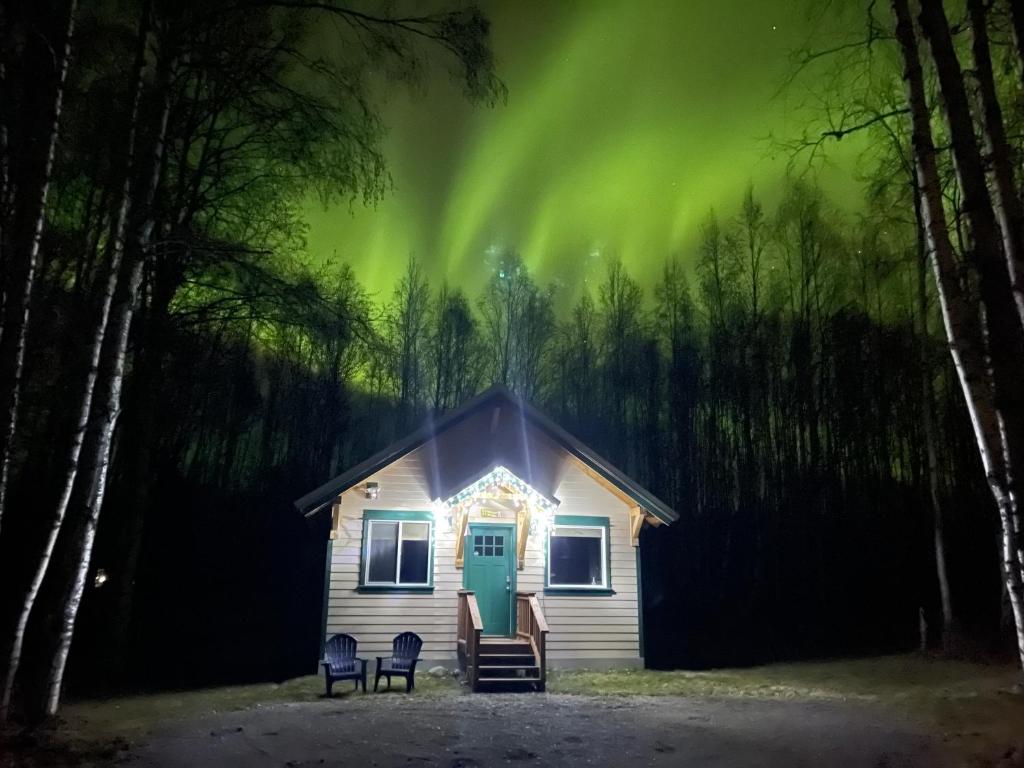 una casa con sillas delante de ella por la noche en Talkeetna Mount Dall Cottage with WiFi&laundry, en Talkeetna