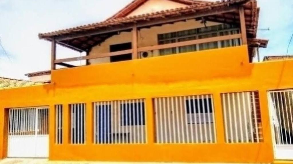 康塞桑達巴拉的住宿－Casa em Conceição da Barra para temporada e Carnaval，黄色的建筑,设有白色的门窗
