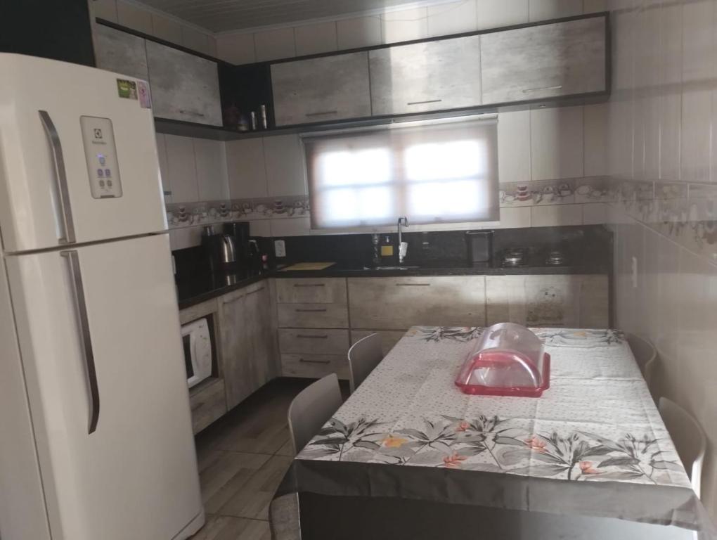 a kitchen with a table and a white refrigerator at Casa em imbé in Imbé
