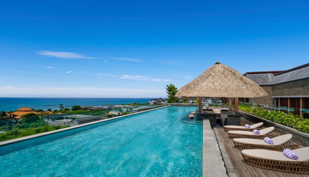 a pool at a resort with lounge chairs and the ocean at Holiday Inn Resort Bali Canggu by IHG in Canggu