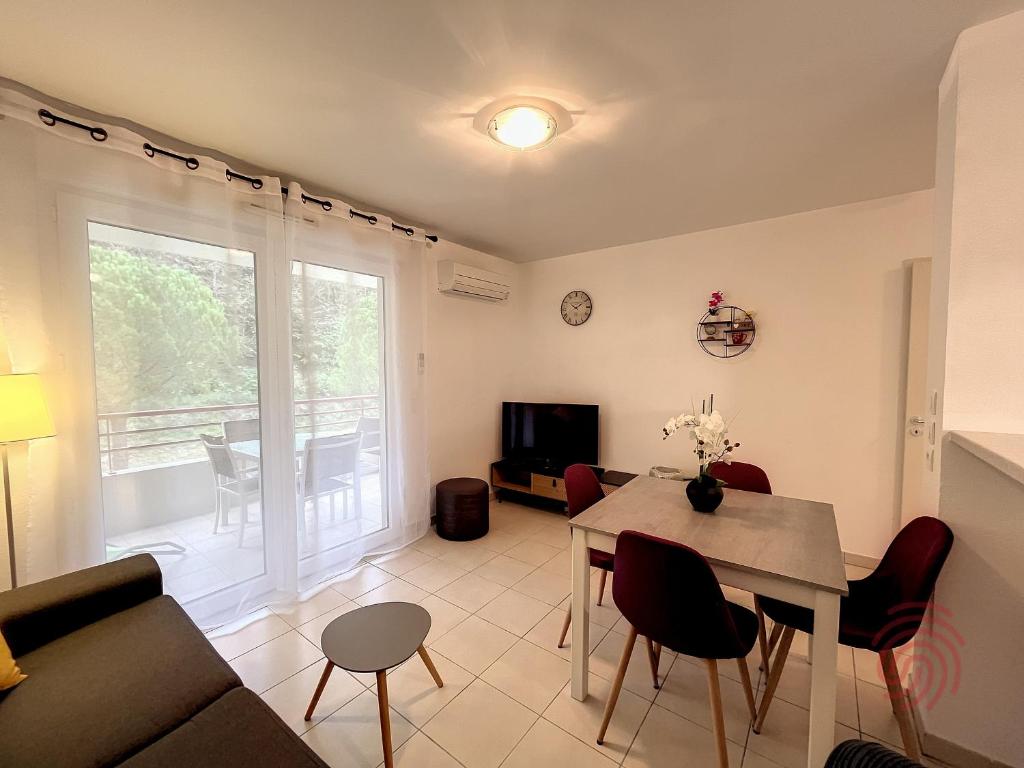 un salon avec un canapé et une table avec des chaises dans l'établissement Appartement F2 climatisé à Lamalou-les-Bains, terrasse, proche centre et thermes, animaux acceptés - FR-1-451-167, à Lamalou-les-Bains