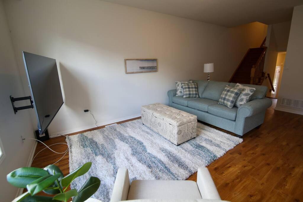 ein Wohnzimmer mit einem blauen Sofa und einem Teppich in der Unterkunft Executive 3 Bedroom townhouse close to the Lake in Hamilton