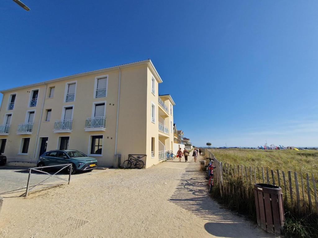 a building with a car parked next to a fence at Appartement Châtelaillon-Plage, 4 pièces, 6 personnes - FR-1-706-11 in Châtelaillon-Plage