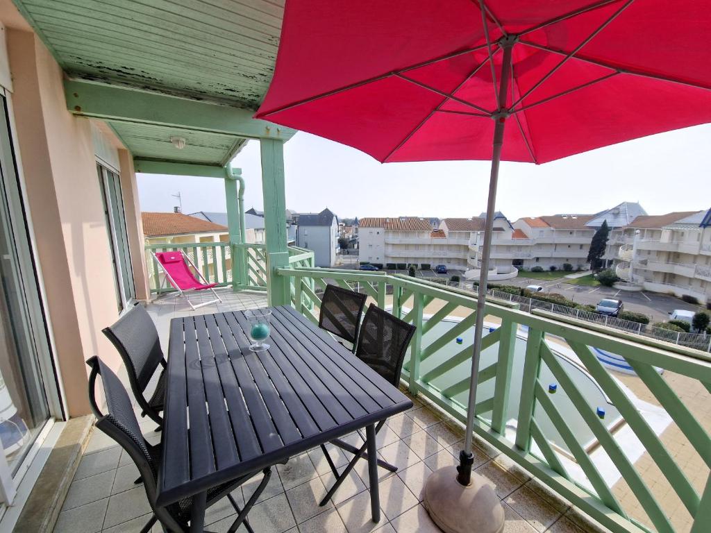 a patio table with a red umbrella on a balcony at Appartement Châtelaillon-Plage, 3 pièces, 6 personnes - FR-1-706-17 in Châtelaillon-Plage