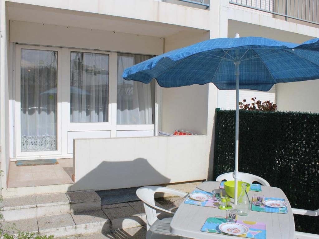- une table avec un parasol bleu sur la terrasse dans l'établissement Studio 4 pers avec Wifi et Animaux admis à Châtelaillon-Plage - FR-1-706-10, à Châtelaillon-Plage