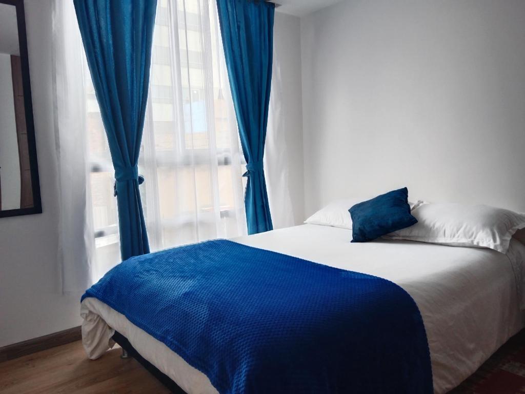Schlafzimmer mit einem Bett mit blauen Vorhängen und einem Fenster in der Unterkunft Apartamento Nuevo - Centro Internacional Bogotá in Bogotá