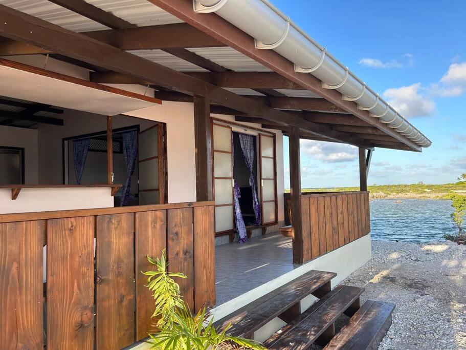 ein Haus mit einer Holzterrasse am Wasser in der Unterkunft Rangiroa Bliss in Tiputa