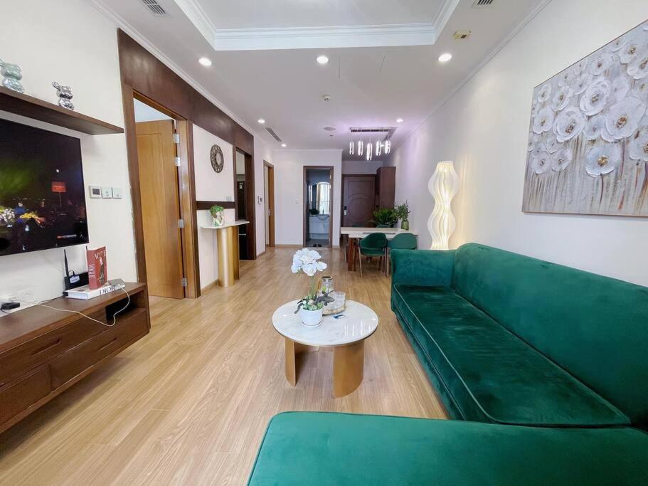 ein Wohnzimmer mit einem grünen Sofa und einem Tisch in der Unterkunft LuxurySunlit/2bed/P10Times in Hanoi