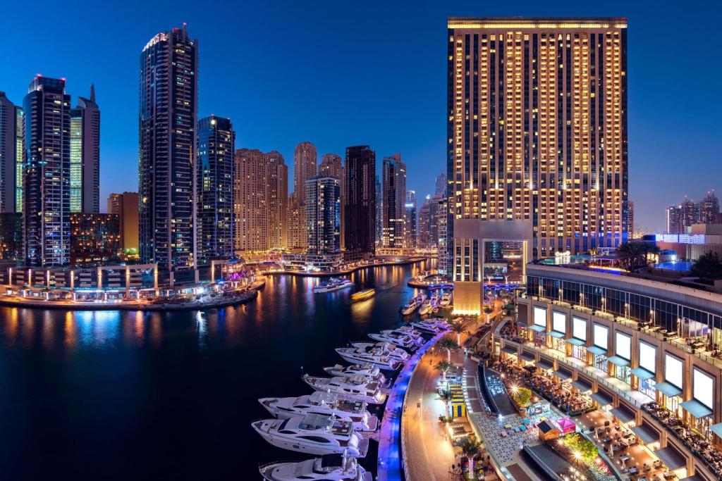 JW Marriott Hotel Marina في دبي: أفق المدينة في الليل مع القوارب في الماء