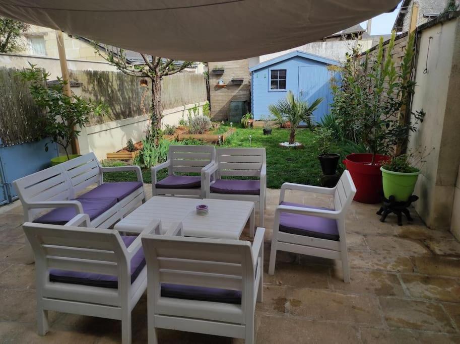 un grupo de sillas blancas y una mesa con asientos morados en Chaleureuse maison de ville avec parking gratuit, en Chinon