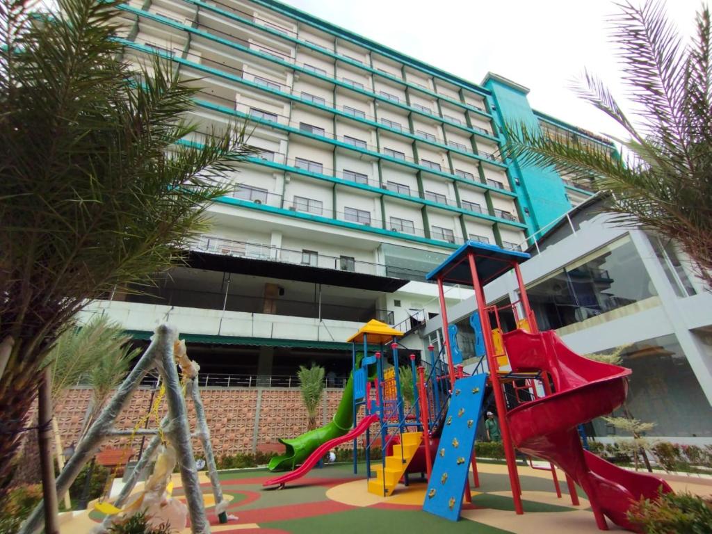 un parque infantil frente a un gran edificio en Hotel Gren Alia Jakarta en Yakarta