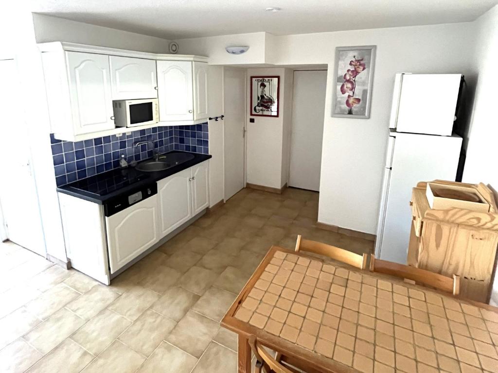 een keuken met witte kasten en een witte koelkast bij Appartement Cap d'Agde, 3 pièces, 6 personnes - FR-1-769-4 in Cap d'Agde