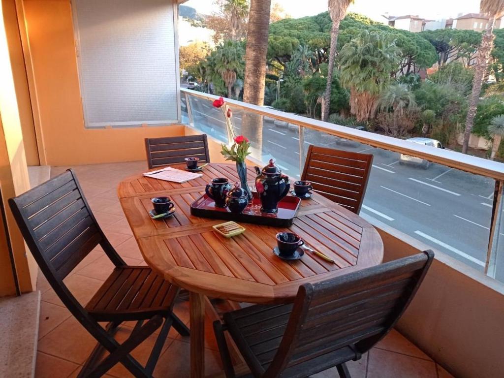 einen Holztisch und Stühle auf einem Balkon mit einem Tisch in der Unterkunft Appartement Le Lavandou, 2 pièces, 4 personnes - FR-1-308-185 in Le Lavandou