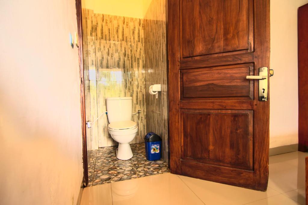 a bathroom with a toilet through a door at Hotel Bonne Nuit in Labuan Bajo