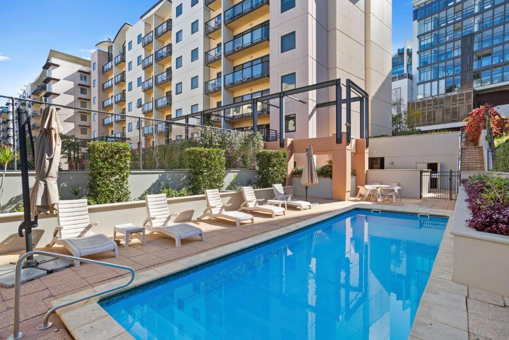 a swimming pool with lounge chairs and a building at City View 1br Gem On Mounts Bay Road in Perth