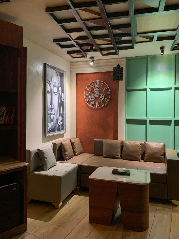 a living room with a couch and a clock at Kuruva Island Resort And Spa - By KABINI BREEZE, Wayanad in Mananthavady