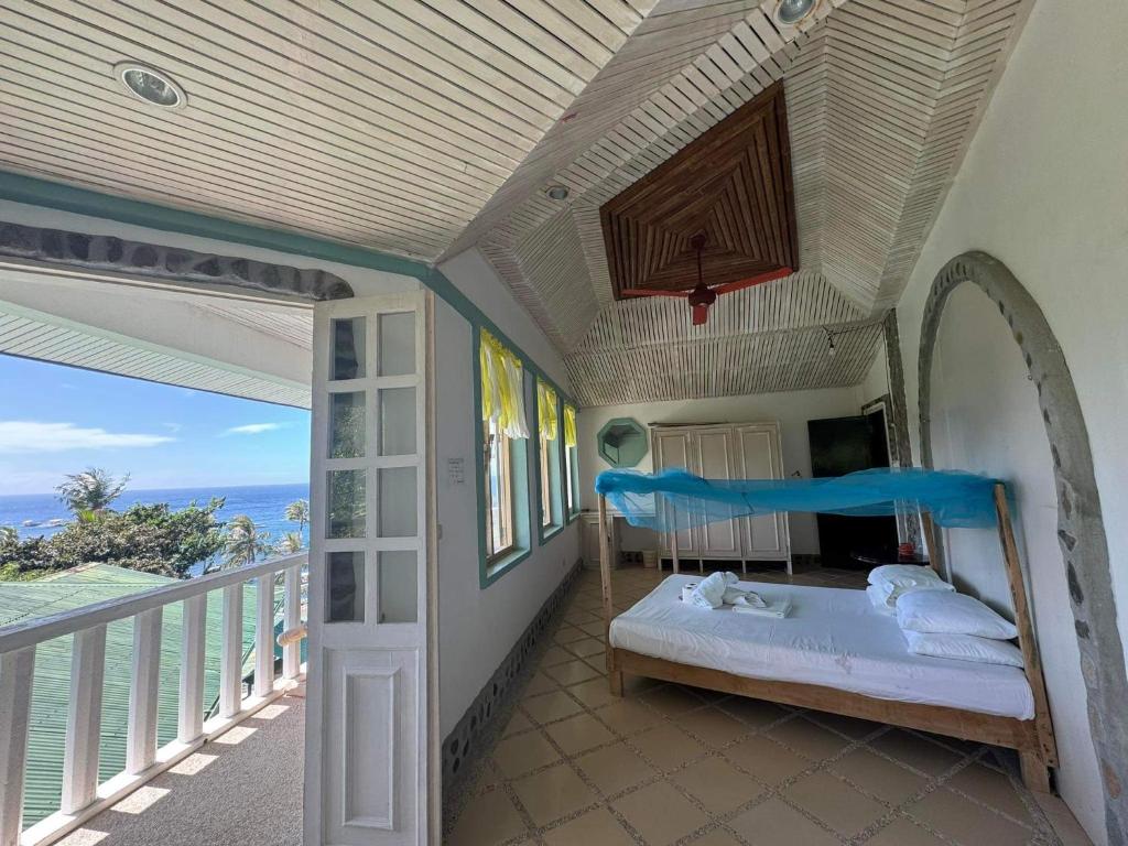 Liberty's Community Lodge and Diving في دوماغيتي: غرفة نوم مع سرير وشرفه مع المحيط