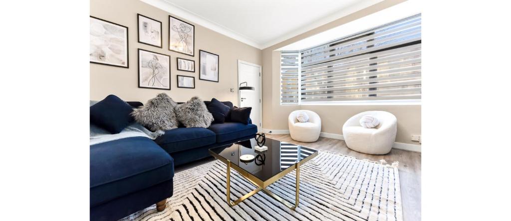 uma sala de estar com um sofá azul e uma mesa em Serene, Stylish, Spacious Brand New for 2023! em Londres