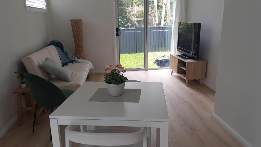 a living room with a white table and a tv at Kooyong in Northmead