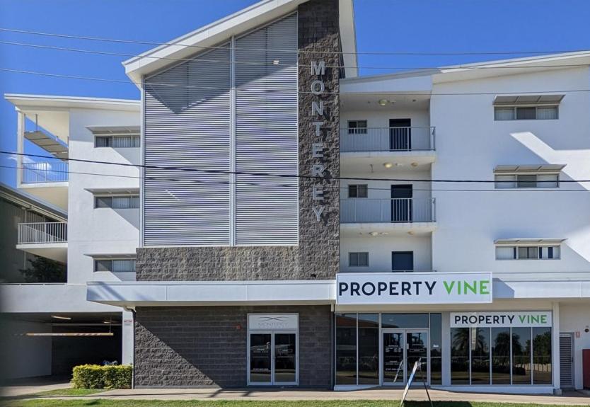 a white building with a property wing sign in front of it at Monterey Apartments Moranbah in Moranbah