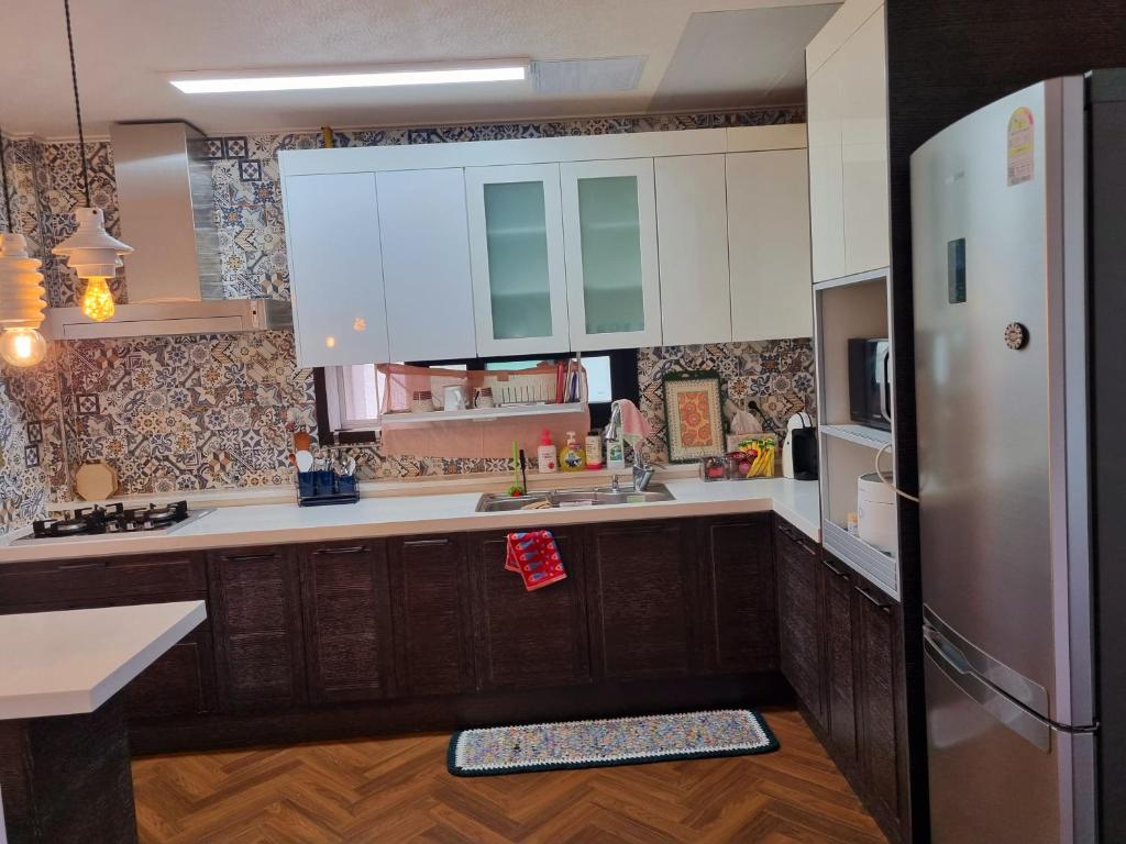 a kitchen with white cabinets and a stainless steel refrigerator at Food House in Andong
