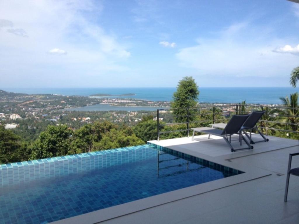 a swimming pool with two chairs and a view of the ocean at Great Sea View Mountain Villa Koh samui in Amphoe Koh Samui