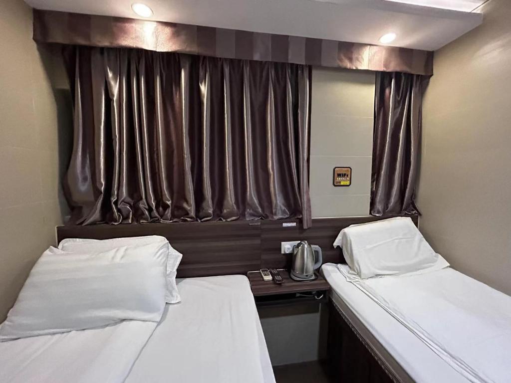 2 camas en una habitación pequeña con ventana en 香港名都商务旅馆 self-check-in en Hong Kong